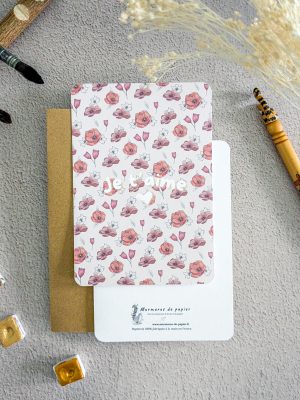 Carte postale avec un motif fleuri dans les tons rouges et au centre le message "Je t'aime"