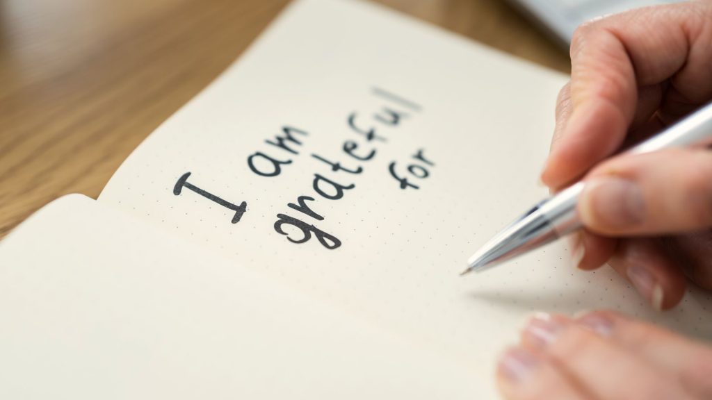 Photo d'un carnet ouvert avec la phrase "I am grateful for". Photo qui illustre cet article avec 10 questions de journaling pour cultiver la gratitude