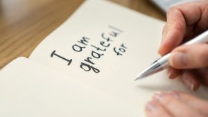 Photo d'un carnet ouvert avec la phrase "I am grateful for". Photo qui illustre cet article avec 10 questions de journaling pour cultiver la gratitude
