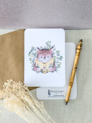 photo qui présente la carte postale "Jardin du chat lecteur" représentant un chat entrain de lire au milieu de la nature