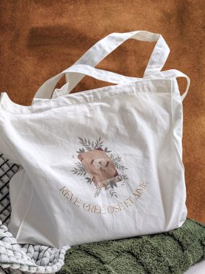tote bag artiste illustré "rêve, crée, ose et aime" posé sur des coussins et vu de face
